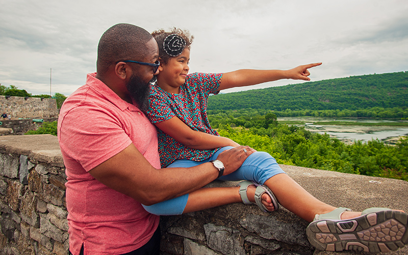 Little girl with her father looking at Lake Champlain from the fort walls