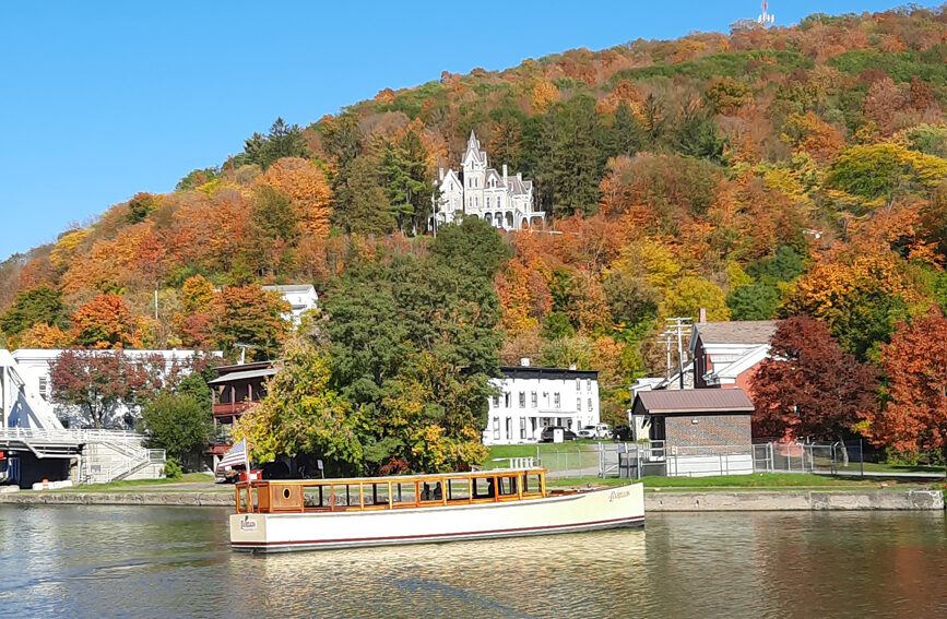 carillon tour boat in front of Skene Manor and fall foliage