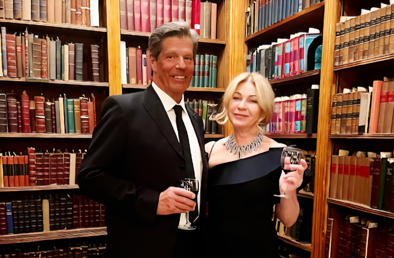 couple standing with drinks in front of bookshelf