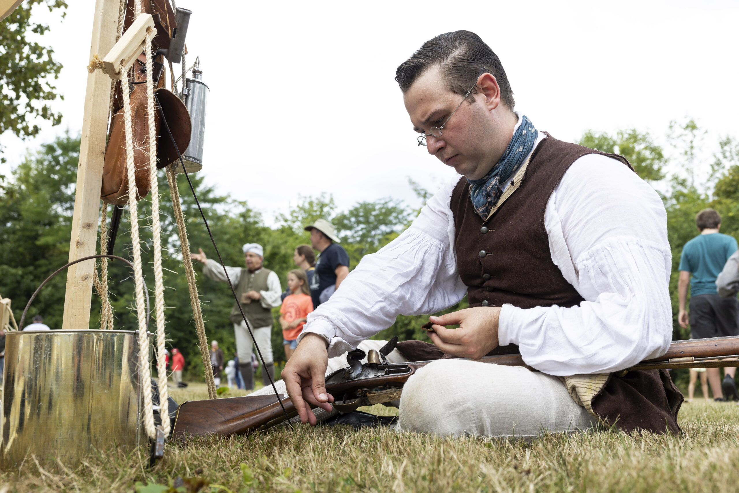 soldier sitting in grass doing musket maintenance