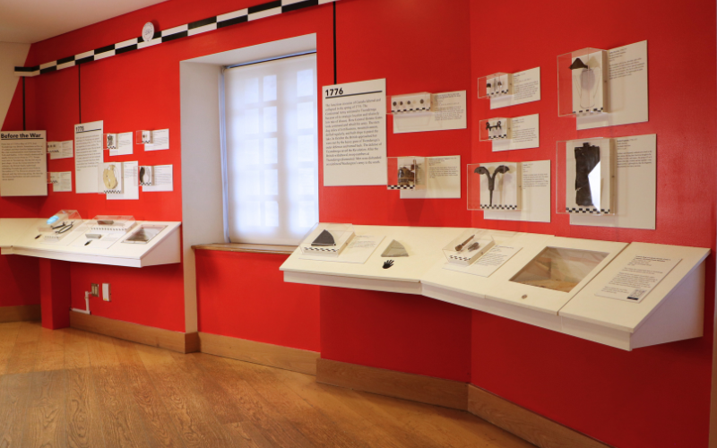 Red room interior with exhibit cases of archaeological artifacts on the wall and countertops