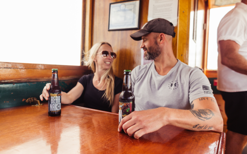 male and female sharing a beer aboard the Carillon Boat during happy hour on Lake Champlain